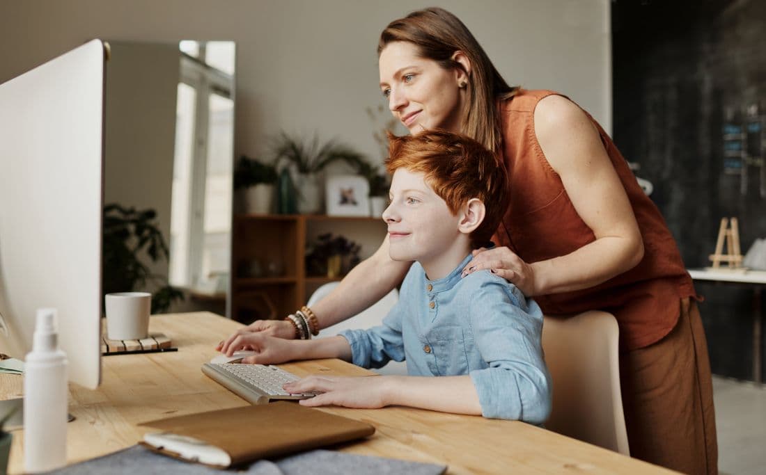 A child working at a computer at home with a parent helping